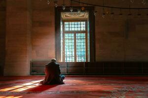 islámico concepto foto. musulmán hombre Orando en el mezquita y luz de sol rayos foto
