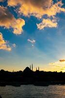 islámico foto. silueta de suleymaniye mezquita a puesta de sol con nublado cielo foto