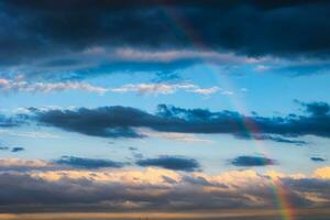 Rainbow and partly cloudy sky on the background photo