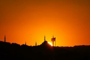 Istanbul silhouette at sunset. Mosque and minarets with flag. photo
