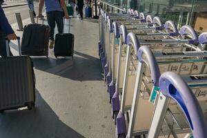 Row of Luggage trolleys or Luggage carts or airport trolleys with people photo