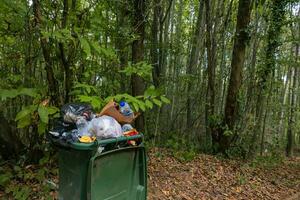 Full trash bin in the forest. Garbage pollution in the forest concept photo