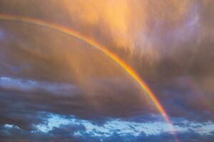 arco iris a puesta de sol. parcialmente nublado cielo en el antecedentes foto