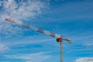 Construction background photo. Tower crane isolated on partly cloudy sky photo