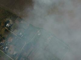 Top view of the small village. Smoke from the burning of straw is spread over the village photo