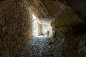 L'Aquila, Italy-august 12, 2021-ruins of the Hermitage of the Holy Spirit an ancient church dug into a cliff with a well-preserved fresco, altar and hermit's cells. photo