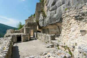 L'Aquila, Italy-august 12, 2021-ruins of the Hermitage of the Holy Spirit an ancient church dug into a cliff with a well-preserved fresco, altar and hermit's cells. photo