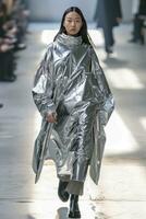 AI Generated In the spotlight at high fashion week, the Asian fashion model struts the runway in stunning metallic silver clothing photo