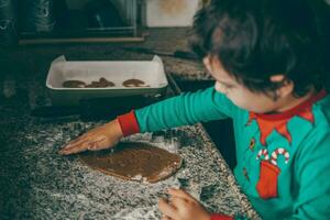 boy and his mom immerse themselves in the holiday spirit, joyfully preparing Christmas gingerbread photo