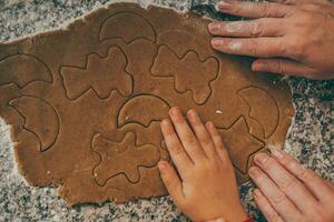 un mamá y su hijo compartir el emoción de preparando Navidad pan de jengibre. foto