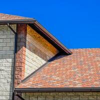 The house is made of beige bricks, the roof is covered with bitumen shingles. Metal plastic windows on the house. photo