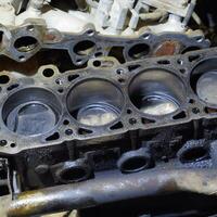 The cylinder block of the four-cylinder engine. Disassembled motor vehicle for repair. Parts in engine oil. Car engine repair in the service photo