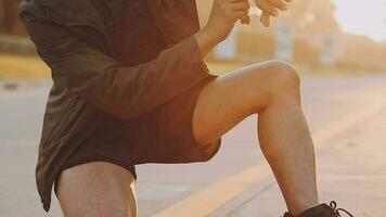 Attractive young man stretching in the park before running at the sunset focus on shoes video