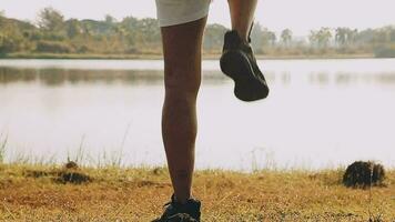 atraente jovem homem alongamento dentro a parque antes corrida às a pôr do sol foco em sapatos video