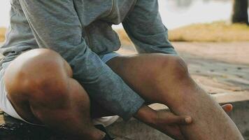 Attractive young man stretching in the park before running at the sunset focus on shoes video