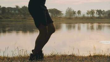 Attractive young man stretching in the park before running at the sunset focus on shoes video