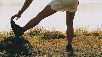 Attractive young man stretching in the park before running at the sunset focus on shoes video