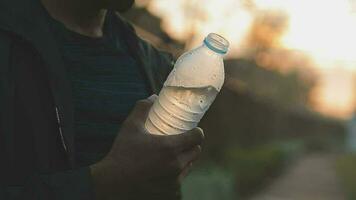 atleta uomo potabile acqua a partire dal un' bottiglia dopo jogging nel il città su un' soleggiato giorno video