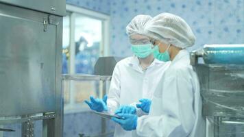 Female factory workers check machine systems at the industrial factory. Women working in clean rooms for beverage and food production. Female worker recording data at the control panel. video