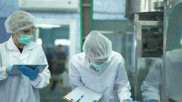 mujer fábrica trabajadores cheque máquina sistemas a el industrial fábrica. mujer trabajando en limpiar habitaciones para bebida y comida producción. hembra trabajador grabación datos a el controlar panel. video