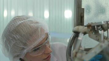 fábrica mujer ingeniero inspeccionando agua dispensador en el máquina. el trabajador cheques el calidad de agua botellas en el máquina transportador línea a el industrial fábrica. video