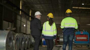 Senior patrão Gerente inspecionando com funcionários engenheiros mulher e africano homem.equipe verificação construção estrutura do fábrica prédio. armazém com aço cobertura estrutura e máquina instalação. video