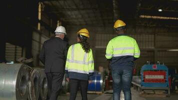 senior baas manager inspecteren met personeel ingenieurs vrouw en Afrikaanse man.team controle bouw structuur van fabriek gebouw. magazijn met staal dak structuur en machine installatie. video