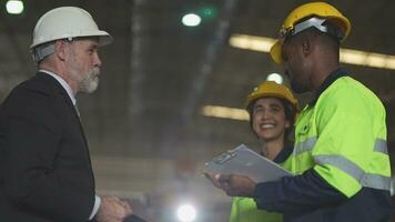 Sénior patron directeur inspecter avec Personnel ingénieurs femme et africain homme.équipe vérification construction structure de usine bâtiment. entrepôt avec acier toit structure et machine installation. video