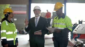 Senior patrão Gerente inspecionando com funcionários engenheiros mulher e africano homem.equipe verificação construção estrutura do fábrica prédio. armazém com aço cobertura estrutura e máquina instalação. video