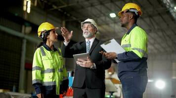 Senior patrão Gerente inspecionando com funcionários engenheiros mulher e africano homem.equipe verificação construção estrutura do fábrica prédio. armazém com aço cobertura estrutura e máquina instalação. video