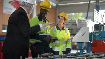 Senior patrão Gerente inspecionando com funcionários engenheiros mulher e africano homem.equipe verificação construção estrutura do fábrica prédio. armazém com aço cobertura estrutura e máquina instalação. video