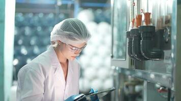 científico mujer trabajador comprobación y supervisión el controlar panel en máquina sistema a el industrial fábrica. hembra trabajador grabación datos a el controlar panel con medida presión de agua nivel. video