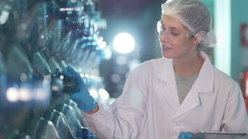 fabriek arbeider controle water flessen in de magazijn Bij de industrieel fabriek. vrouw arbeider opname gegevens Bij de dranken fabricage lijn productie. video