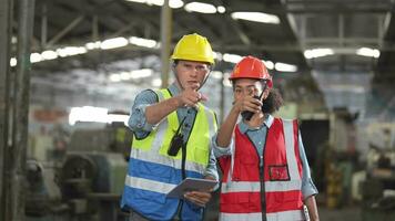 fabriek arbeider mensen inspecteren.vrouwen en Afrikaanse vrouw mensen pratend in voorkant van zwaar machines Bij industrie fabriek. ingenieur in werking en controle. team van Mens in werking Aan plaats inspectie. video