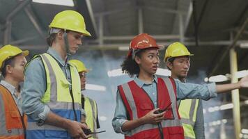 grupo de diversidad fábrica trabajador personas inspeccionando y comprobación local depósito, asiático, blanco caucásico y asiático personas en pesado máquina a industria fábrica. concepto ingeniero operando y control. video