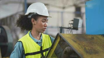 trabalhadores fábrica africano mulher trabalhando às pesado máquina. grupo do pessoas operativo dentro frente do motor fabricado às industrial plantar fábrica. inteligente indústria trabalhador operativo. mulher sorridente e feliz. video