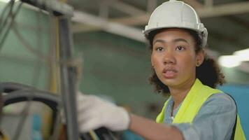 trabajadores fábrica africano mujer trabajando a pesado máquina. grupo de personas operando en frente de motor fabricado a industrial planta fábrica. inteligente industria trabajador operando. mujer sonriente y contento. video