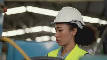 Arbeitskräfte Fabrik afrikanisch Frau Arbeiten beim schwer Maschine. Gruppe von Menschen Betriebs im Vorderseite von Motor hergestellt beim industriell Pflanze Fabrik. Clever Industrie Arbeiter Betriebs. Frau lächelnd und glücklich. video