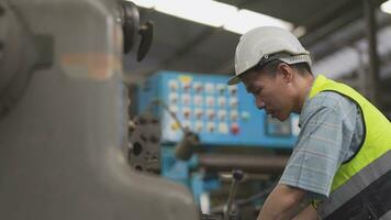 arbetare fabrik asiatisk man arbetssätt på tung maskin. grupp av människor rörelse i främre av motor tillverkad på industriell växt fabrik. smart industri arbetstagare fungerar. kvinna leende och Lycklig. video