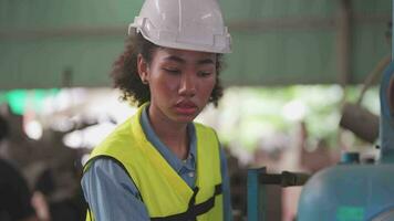 ouvriers usine africain femme travail à lourd machine. groupe de gens en fonctionnement dans de face de moteur fabriqué à industriel plante usine. intelligent industrie ouvrier en fonctionnement. femme souriant et heureux. video