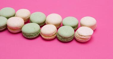 Row of fresh and delicious macaroons dessert on pink background in studio video