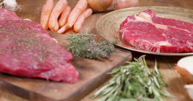 Slide shot of a ribeye steak and a sirolin steak well seasoned. Food composition of raw beef meat, vegetables and spices. video
