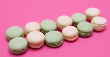 A row of colored macaroons dessert on pink background video