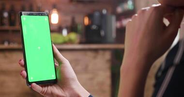 donna focalizzata su sua smartphone mentre visualizzazione un' verde schermo. concentrato a il schermo di sua dispositivo. croma chiave diapositiva sparo. video