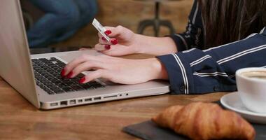 dichtbij omhoog van de handen van een jong vrouw maken een betaling gebruik makend van haar kaart. betalen voor boodschappen doen online. betalen rekeningen. online betalen met de bank kaart. video