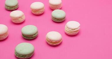 Delicious and sweet macaroons in different colors on pink background in studio video