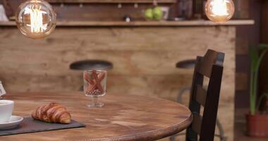 Close up revealing shot of a cup of espresso americano and french croissant. Slide from right to left. Empty bar and table. video