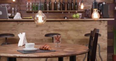 faire glisser coup de droite à la gauche de une café magasin table avec une tasse de café sur il. ancien bar. deux chaises et une en bois tableau. video