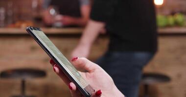 Jeune les femmes main défilement une texte sur sa téléphone intelligent dans une bar. à la recherche pour une important texte sur sa mobile filtrer. video