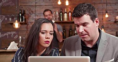 Close up shot of a man and woman looking at a laptop screen and discussing. Slide shot from right to left of a female and a male business partners. video